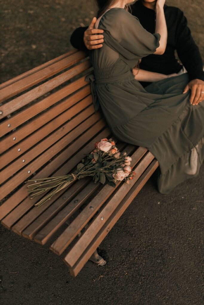 A woman sitting on a wooden bench next to a man