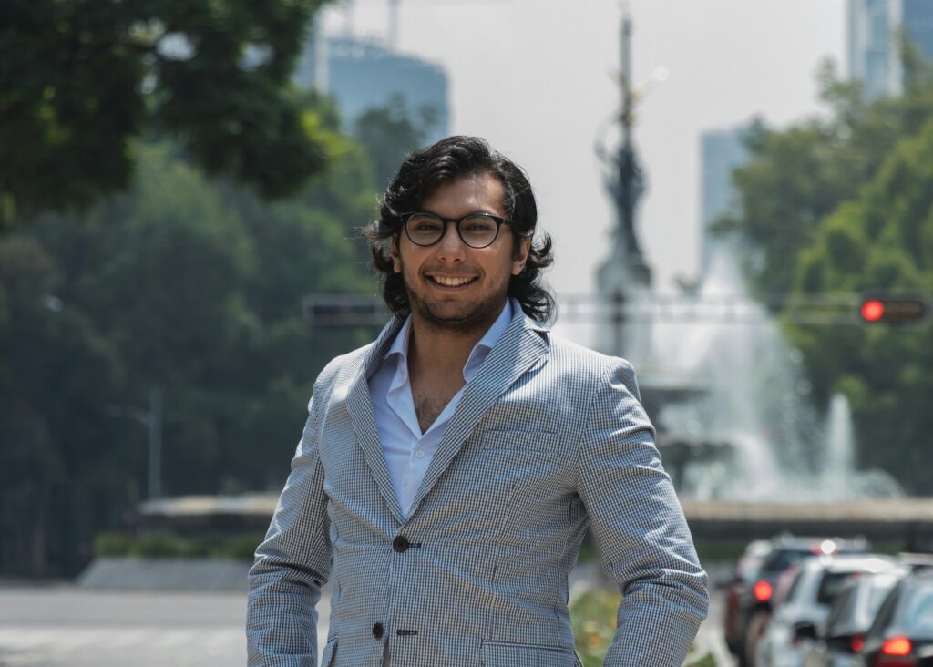 a man in a suit standing in front of a fountain