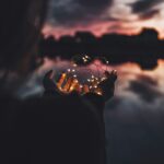 person holding turned on string lights during nighttime