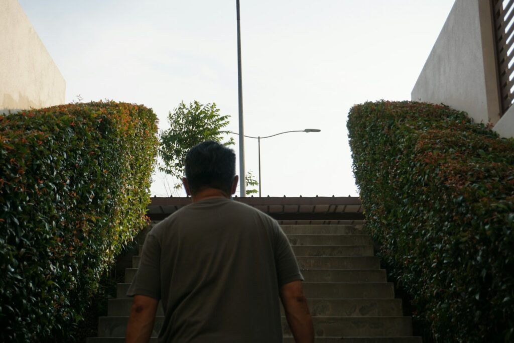 man in gray polo shirt standing near green bush during daytime